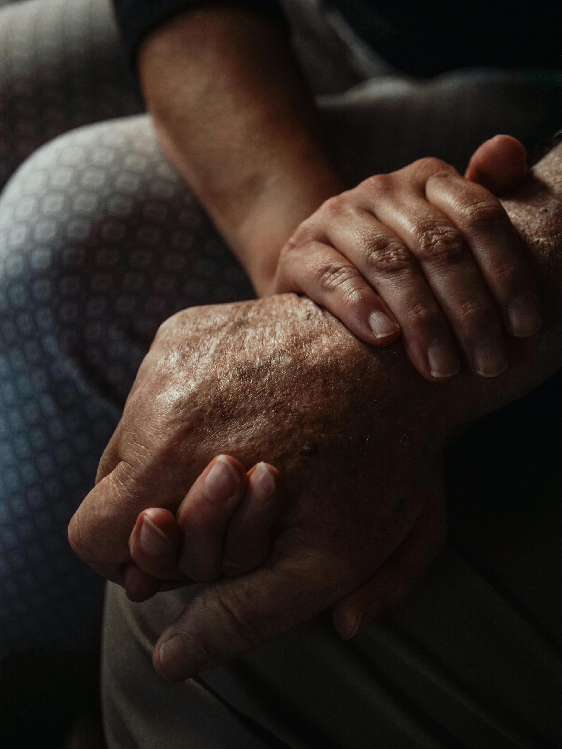 Eine jüngere Person die von einer älteren Person die Hand haltet
